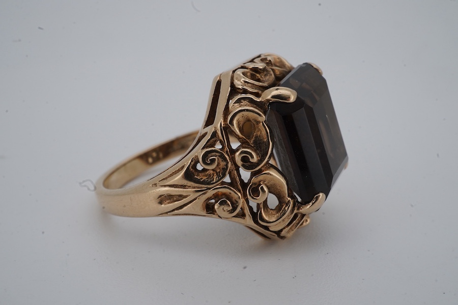 A smoky quartz dress ring, set with a step-cut smoky quartz, to a scrolled mount, size O, stamped PPLd 9CT, numbered, gross weight 6 grams